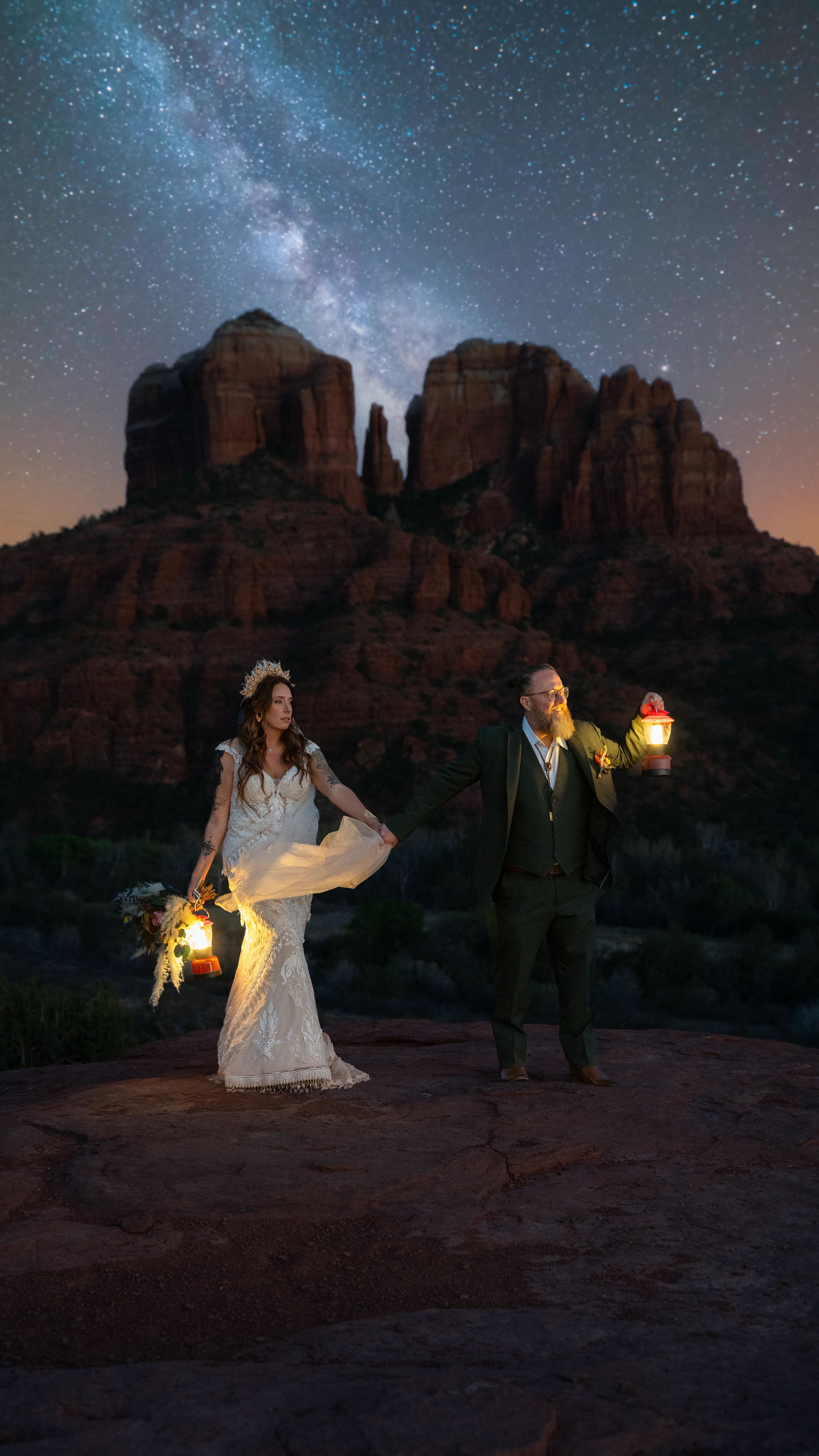 Lauren and Ben holding lanterns beneath the Milky Way and Cathedral Rock at their Sedona wedding